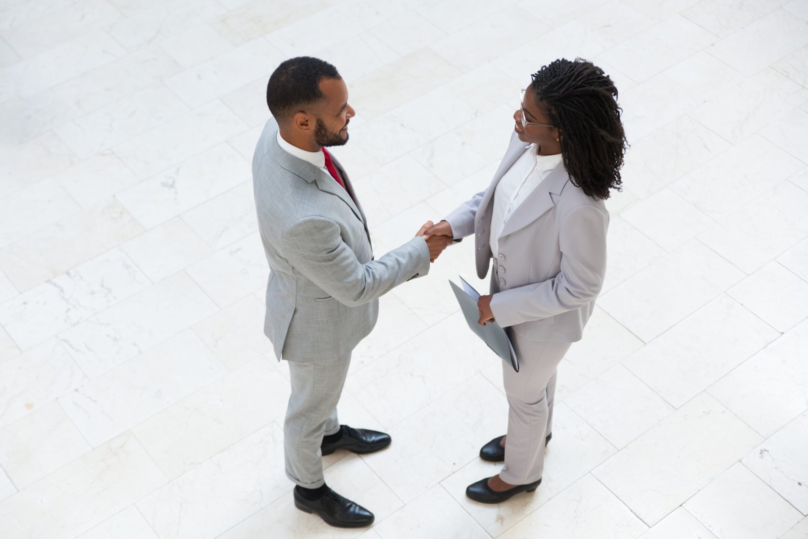 HR manager welcoming successful candidate in office hallway. Business man and woman standing and shaking hands. Hiring concept